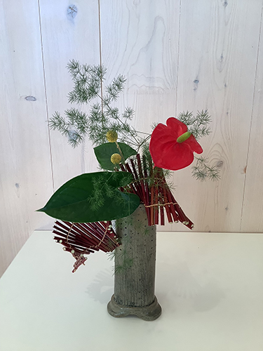 Red anthurium in tall vase with a wrapped tatami mat